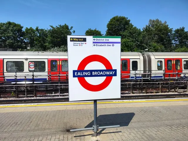 Ealing Broadway sign at a London Underground platform on a sunny day.