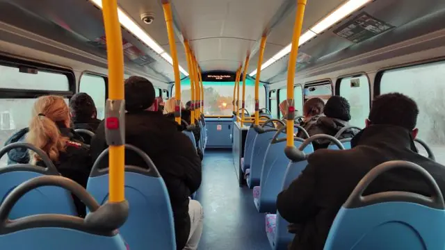 Passengers riding a crowded double-decker bus in London.