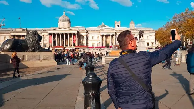 A bustling day at Trafalgar Square with tourists and lion statues in London.