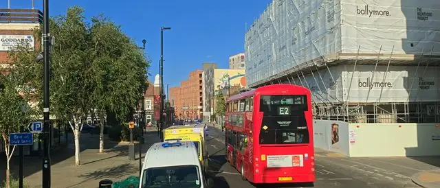A busy London street with a red bus and emergency vehicles.
