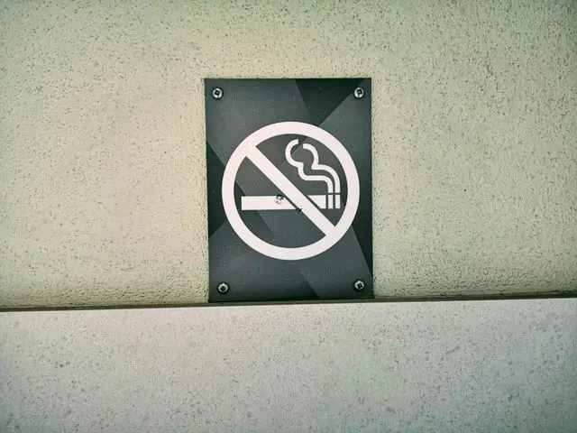 A no smoking sign on a textured wall in London.
