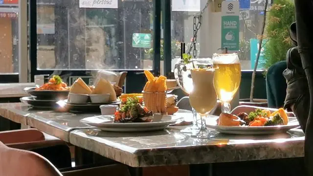 Plates of food and drinks on an outdoor café table.
